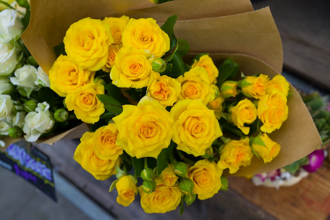 a bouquet of yellow roses sitting on top of a wooden table